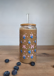 Glas mit buntem Heidelbeer-Muster, gefüllt mit einem Kaffee-Getränk und einem Strohhalm.